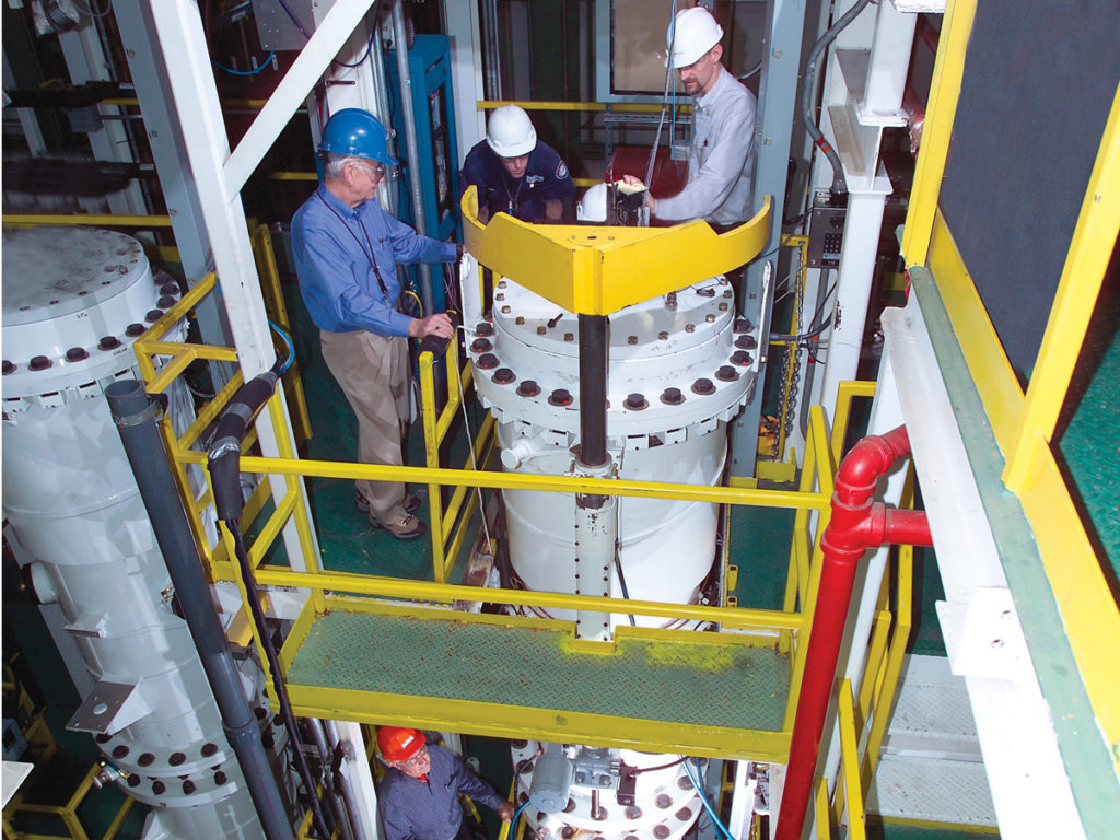 Workers inspecting a centrifuge in a test stand